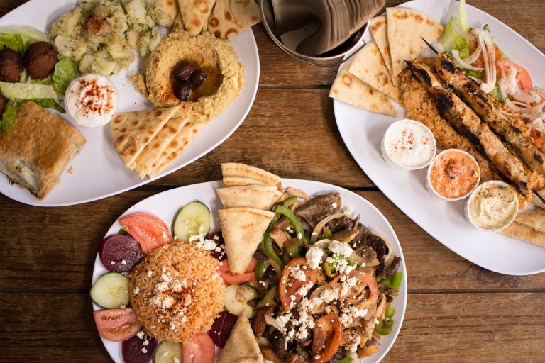 An image showcasing three plates filled with an assortment of meze, including dolmas, hummus, and other Turkish appetizers