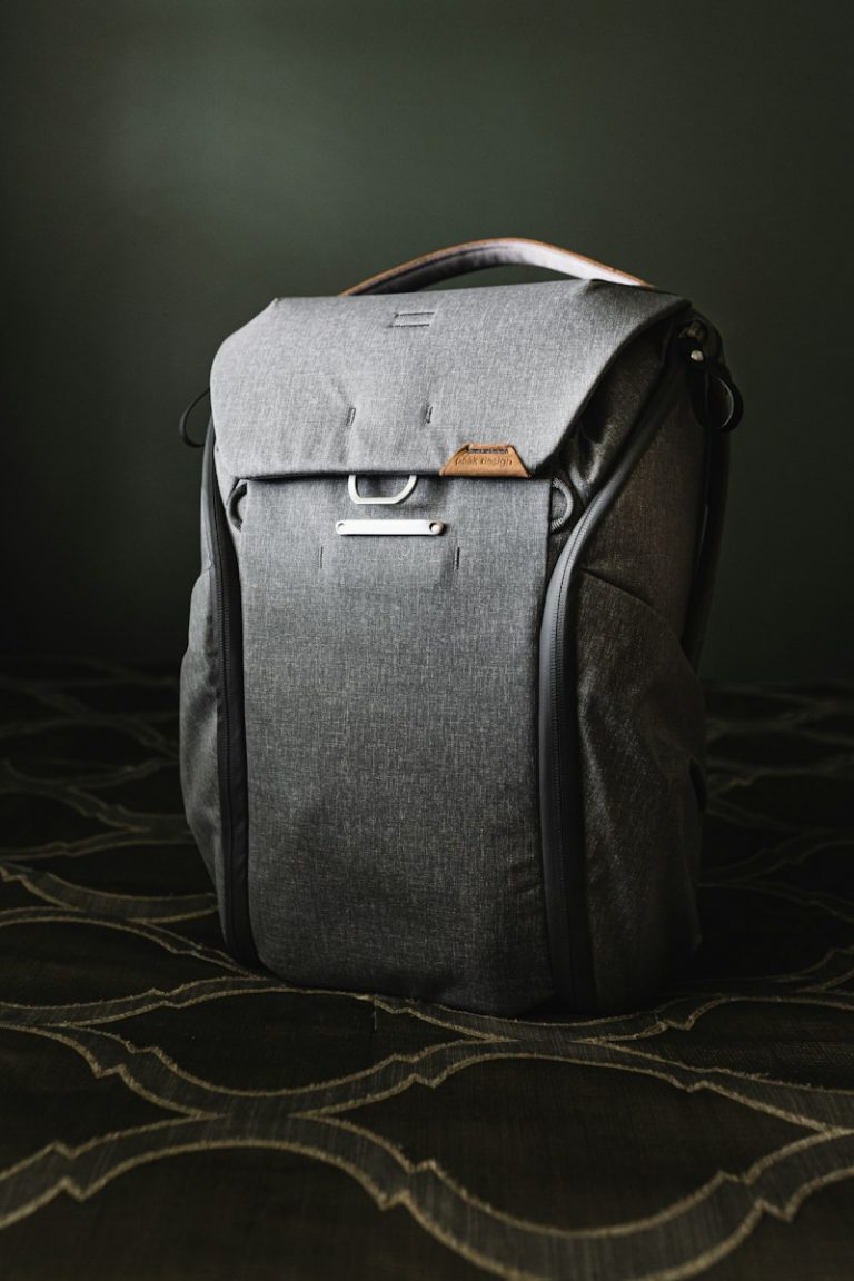 Elegant gray leather backpack on a brown and white floral textile backdrop